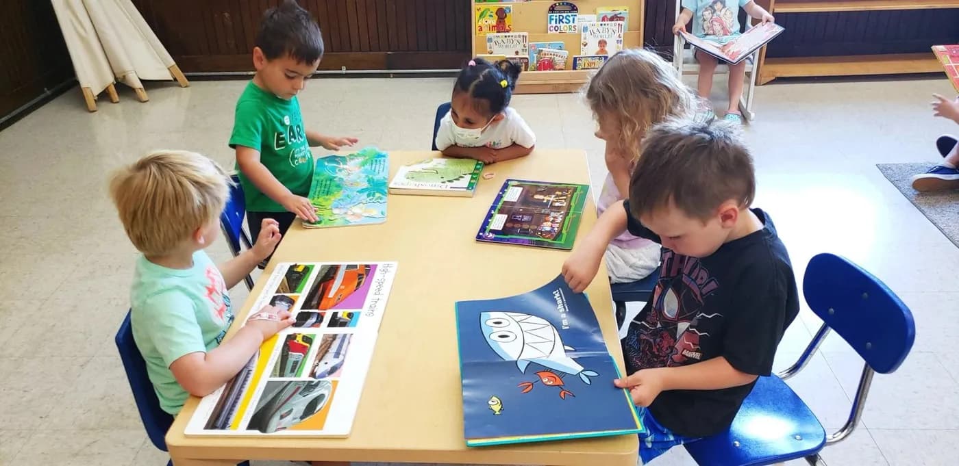 Children looking at picture books together at a table at Child Garden Montessori