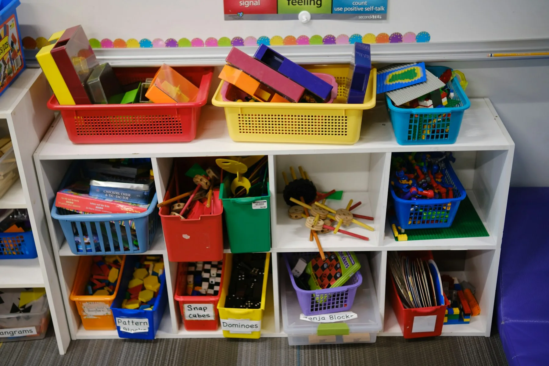 Shelves of colorful storage bins holding educational toys in a classroom.