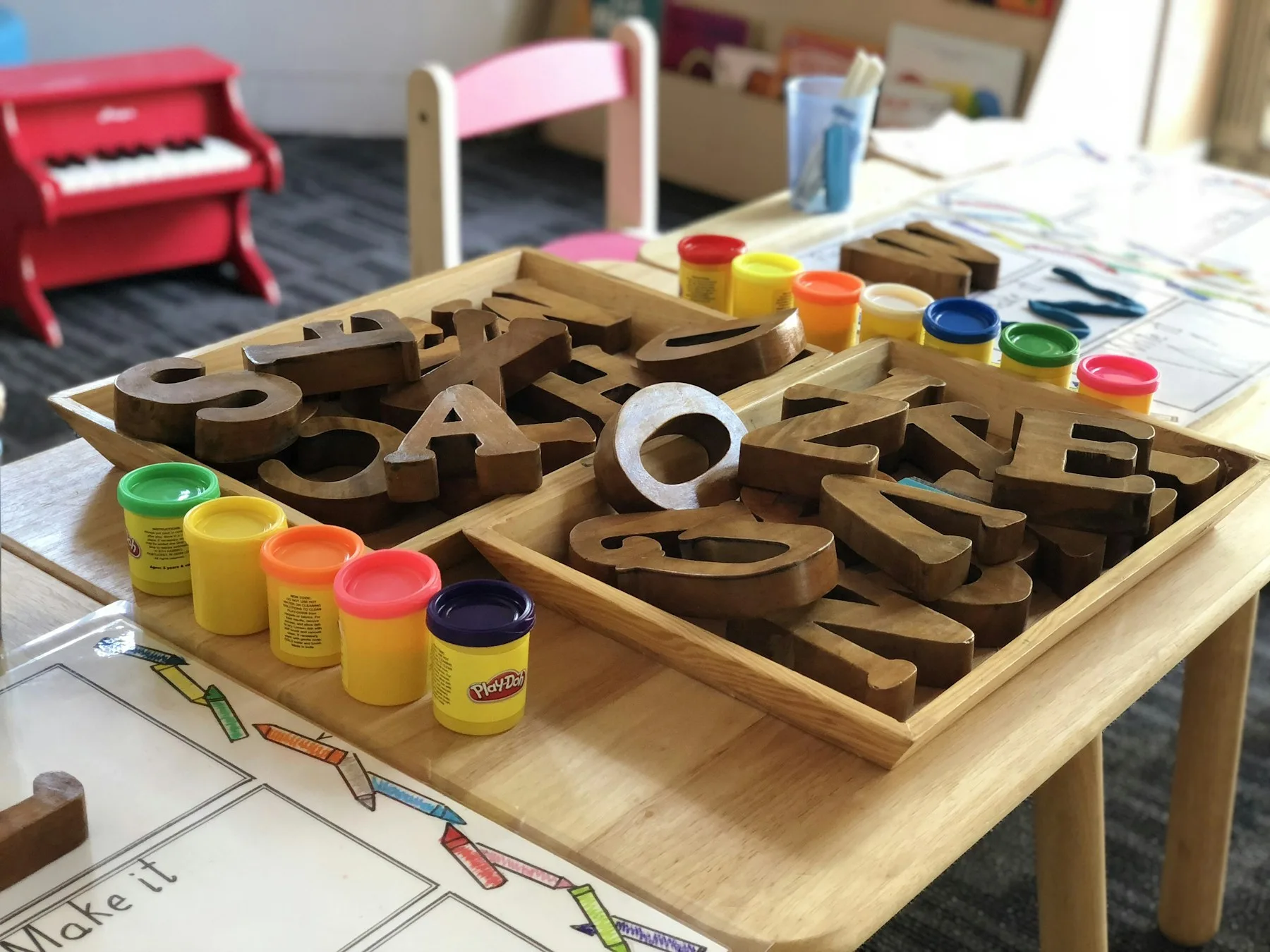 Wooden letters in a tray on a child-height table in a preschool classroom.