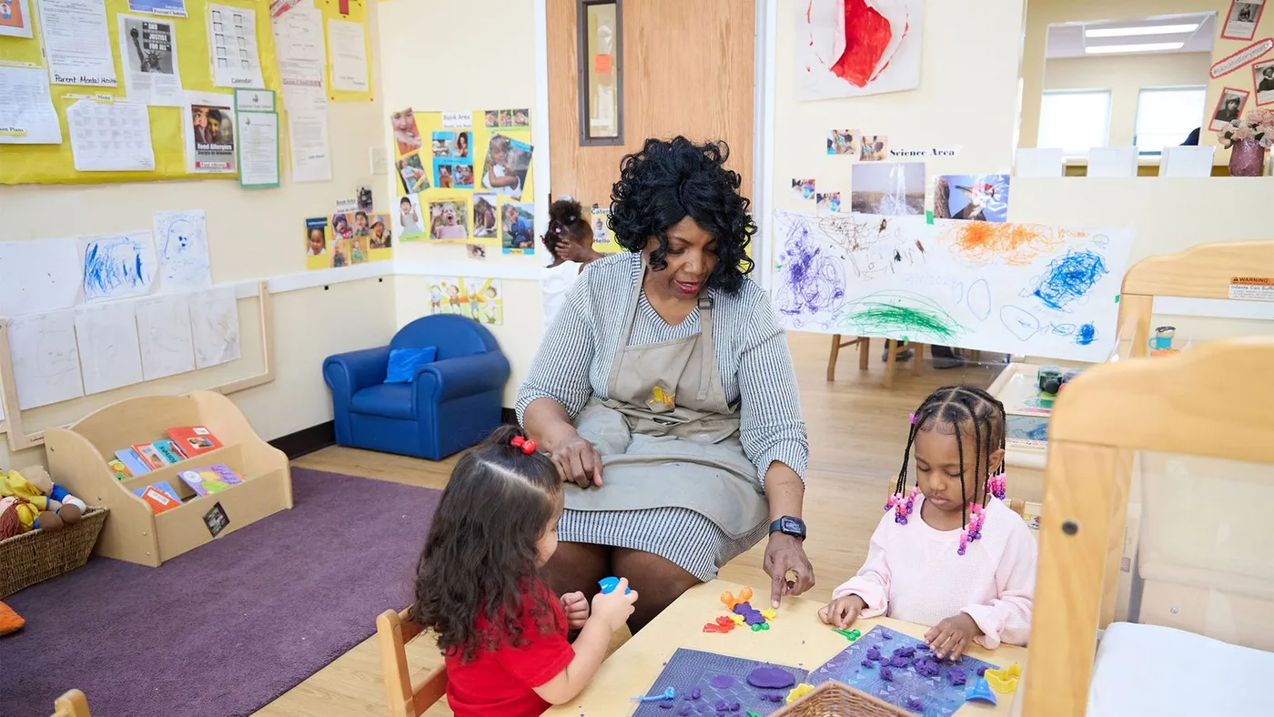 Teacher working with two children at a table at Mary Crane Center