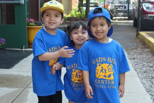 Three children in Gads Hill Center t-shirts and caps on a sidewalk