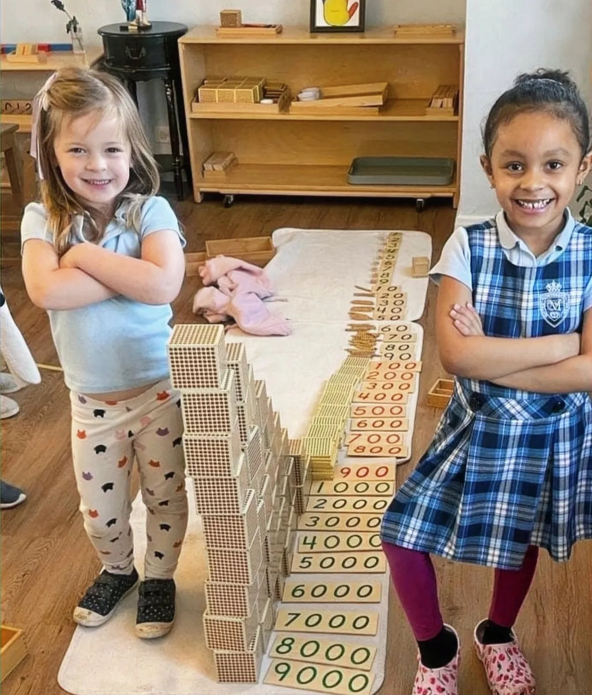Two preschoolers standing behind Montessori golden bead materials at Montessori Gifted Prep