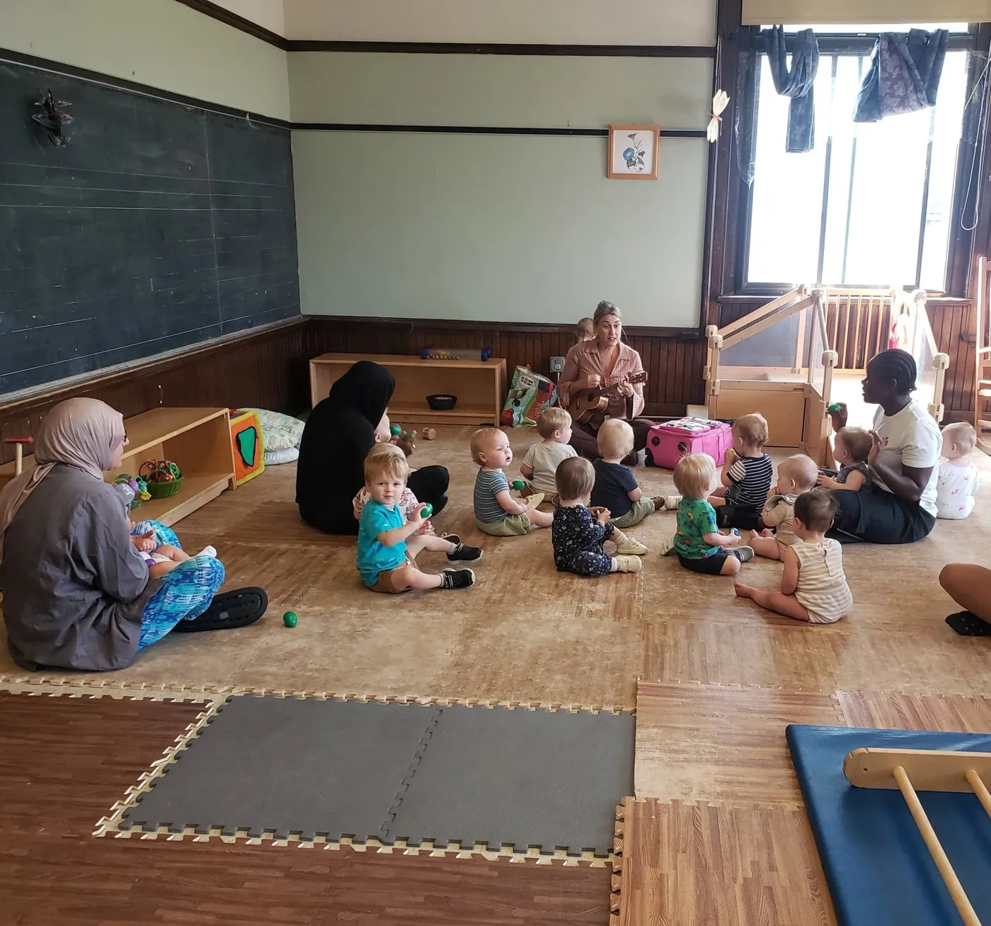 Teachers and babies sitting together on the floor of the infant room at Child Garden Montessori