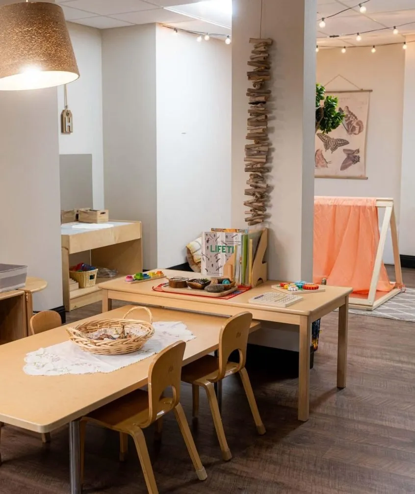 Child-sized tables and shelves of natural materials in a classroom at Kinderberry Hill downtown Minneapolis