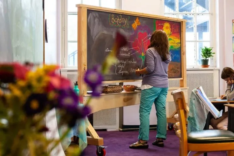 Child drawing on a chalkboard in a bright early childhood classroom at City of Lakes Waldorf School