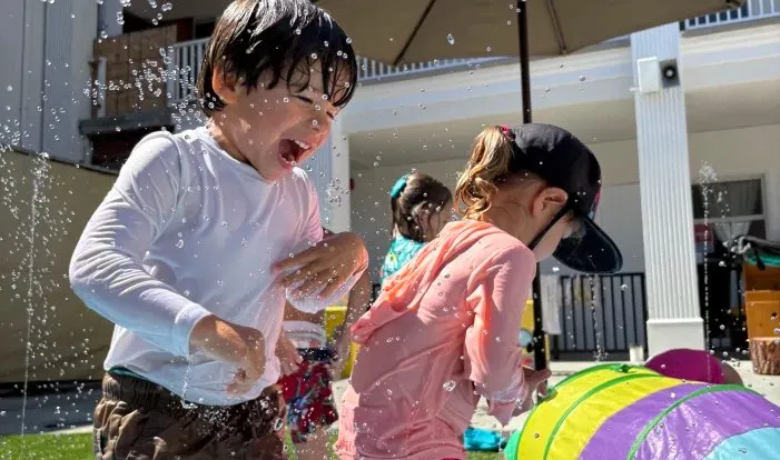 Children playing in the water outside at the Red Brick Preschool