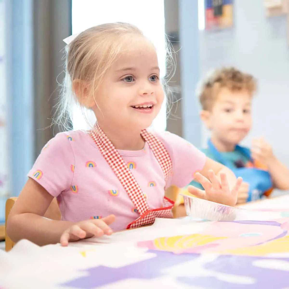 A child smiling at a table during an activity at the SDJA Early Childhood Center