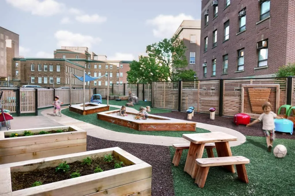Outdoor play yard with garden beds at Queen’s Park Child Care Centre